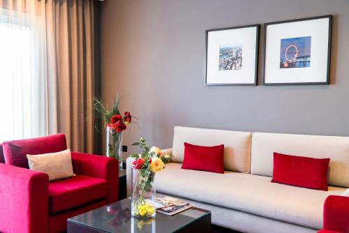 a living room with a couch and two red chairs at Hôtel Tamuda Beach in M'diq