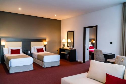 a hotel room with two beds and a desk at Hôtel Tamuda Beach in M'diq