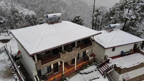 a house with snow on top of it at Boros Resorts Binsar in Almora