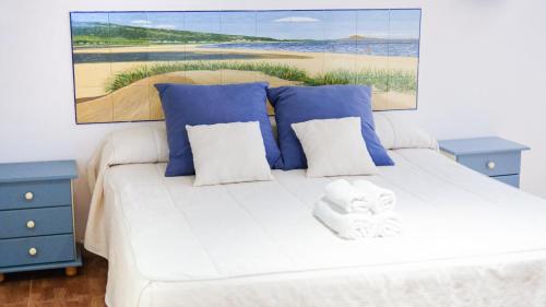 a bedroom with a white bed with blue tables and a painting at Hotel La Torre in Tarifa