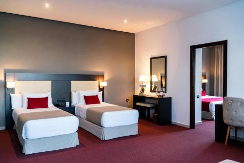 a hotel room with two beds and a desk at Hôtel Tamuda Beach in M'diq