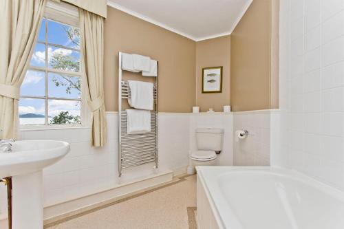 a white bathroom with a sink toilet and a window at The Creggans Inn in Strachur