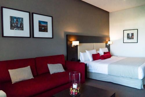 a hotel room with a bed and a red couch at Hôtel Tamuda Beach in M'diq