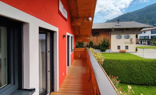 a red and white building with a wooden walkway at Landhaus Elto in Kaprun