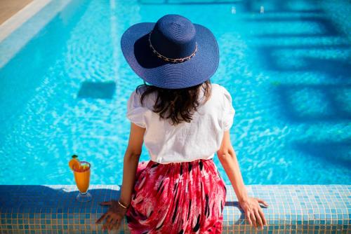 a little girl in a hat standing next to a swimming pool at Hôtel Tamuda Beach in M'diq