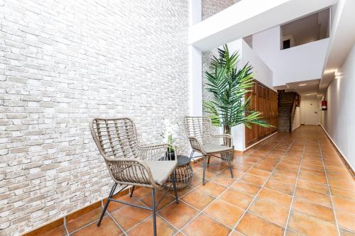 a hallway with chairs and a table and a brick wall at Apartments Urban Arrecife in Arrecife