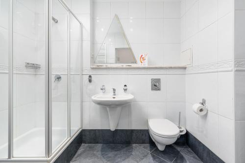 La salle de bains est pourvue d'un lavabo, de toilettes et d'une douche. dans l'établissement JANTAR APARTAMENTY -Port Kołobrzeg- Westerplatte z garażem, à Kołobrzeg
