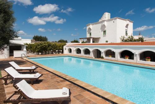 a swimming pool with lounge chairs and a building at Masseria Il Melograno in Monopoli