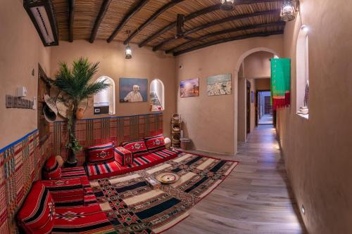a living room with red chairs and a rug at Bait Alharah in Al Jināh