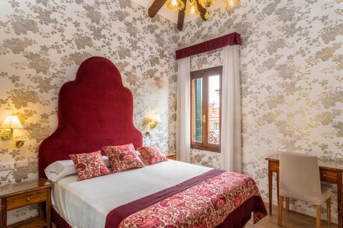a bedroom with a bed with a red headboard and a window at Hotel Villa Rosa in Venice