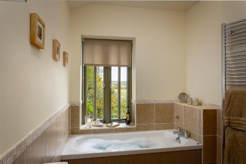 a bath tub in a bathroom with a window at The Granary at Cornish Barn Holidays in Truro