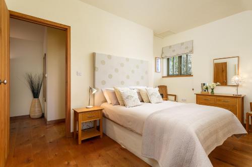 a bedroom with a large bed with white sheets at The Granary at Cornish Barn Holidays in Truro