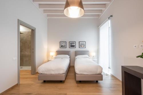 two beds in a bedroom with white walls and wood floors at Borgo di Drugolo in Lonato del Garda