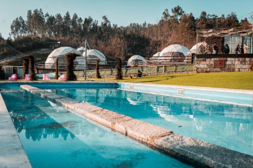 a swimming pool with domes and tents in the background at Guimaglamp in Guimarães