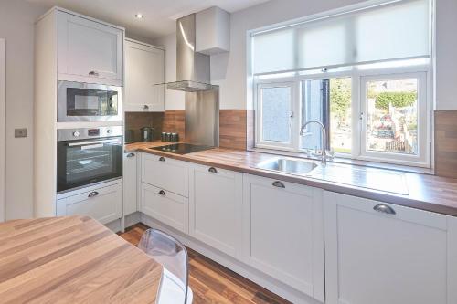 a kitchen with white cabinets and a sink and a table at Host & Stay - Baslow Road, Serviced Apartment in Totley