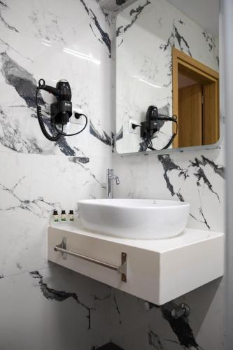 a white bathroom with a sink and a mirror at Alexandros in Giannitsa