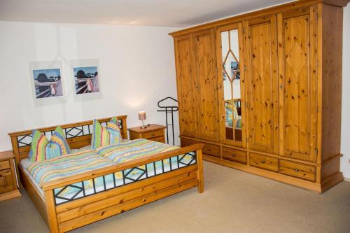 a bedroom with a wooden bed and a large wooden cabinet at Haus Bott in Hilders