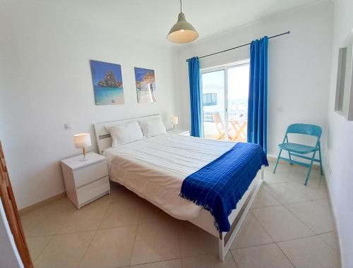 een slaapkamer met een bed, een stoel en een raam bij COLINA FÉRIAS- Garagem & WIFI in Quarteira