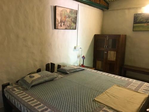 a bedroom with a bed and a dresser at Kamp Kamouflage Kanha in Kānha