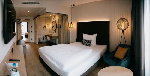 1 dormitorio con 1 cama blanca grande y 1 silla en LOOM Hotel & Skybar, en Eislingen