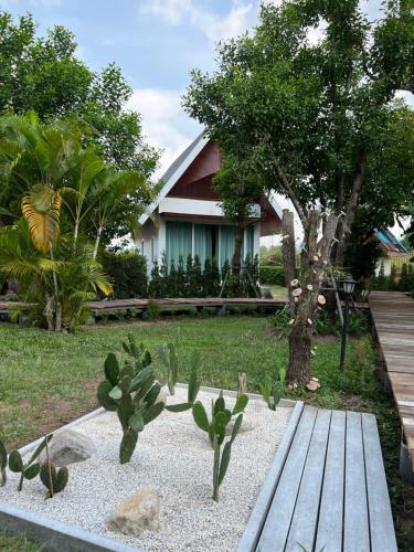 een tuin met een houten bank voor een huis bij Sirilagoona Home Resort in Nong Prue