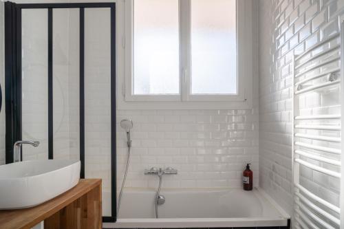 une salle de bain avec une baignoire blanche et un lavabo dans l'établissement Le Manège - Spacieux T2 avec Terrasse au coeur de Nantes, à Nantes