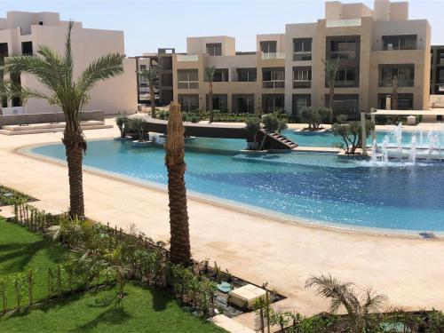 una piscina con palmeras frente a un edificio en Jutta Deluxe 2,5-Bedroom-Apartment Mangroovy-M10 El Gouna, en Hurghada