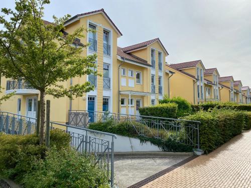 eine Reihe gelber Häuser mit einem Baum und einem Gehweg in der Unterkunft Schloonseevillen - FeWo 13 in Bansin