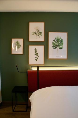 a bedroom with four pictures on a green wall at Campanile Montpellier Ouest - Croix D'Argent in Montpellier