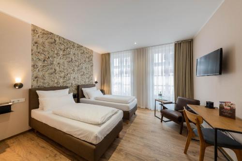 a hotel room with two beds and a desk at Hof Ehrenfels in Mainz