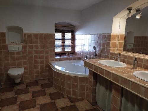 a bathroom with two sinks and a tub and a toilet at Forest Rustic Apartment Brdy in Buková