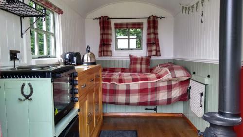a kitchen with a couch in the corner of a room at Shepherd's Lodge - Shepherd's Hut with Devon Views for up to Two People and One Dog in Wrangaton
