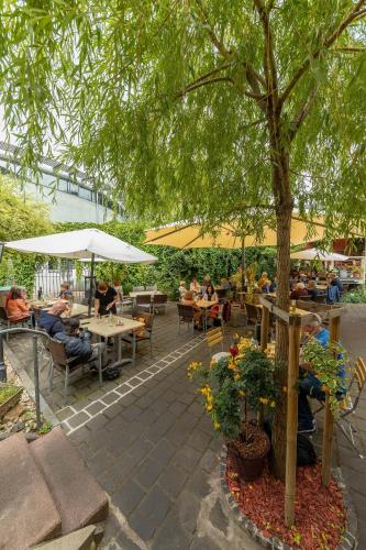 a patio with people sitting at tables and a tree at Hof Ehrenfels in Mainz
