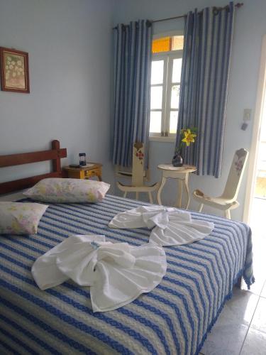 a bedroom with a bed with blue and white sheets at Pousada Oca Porã in Conservatória