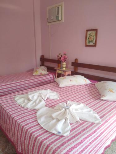 two beds with white bows on them in a room at Pousada Oca Porã in Conservatória