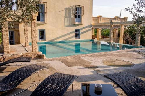 a swimming pool with chairs in front of a building at Villa Luz Casa Valenciana in Alzira