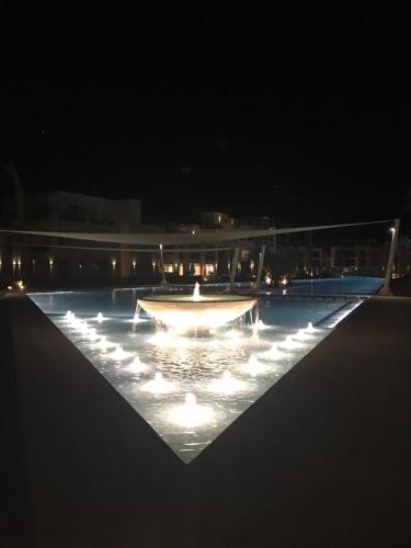 a large pool with a fountain at night at Jutta Deluxe 2-Bedroom-Apartment Mangroovy-M7 El Gouna in Hurghada