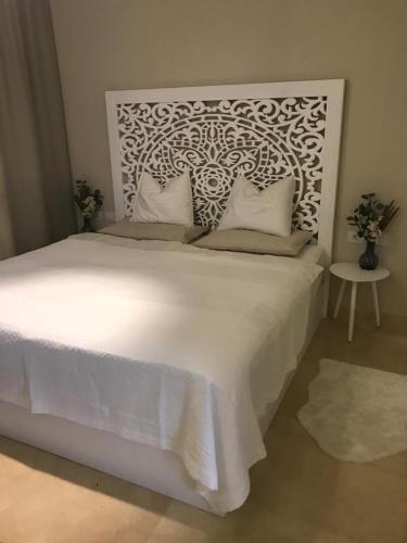 a bedroom with a large white bed with a headboard at Jutta Deluxe 2-Bedroom-Apartment Mangroovy-M7 El Gouna in Hurghada