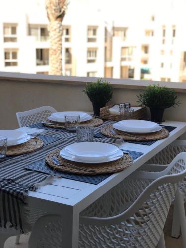 a white table with white plates and glasses on it at Jutta Deluxe 2-Bedroom-Apartment Mangroovy-M7 El Gouna in Hurghada