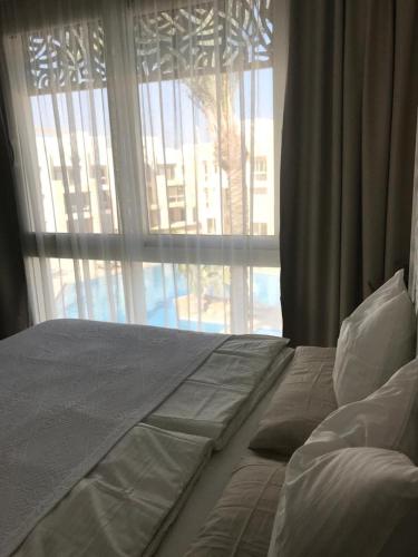 a bed in a bedroom with a large window at Jutta Deluxe 2-Bedroom-Apartment Mangroovy-M7 El Gouna in Hurghada