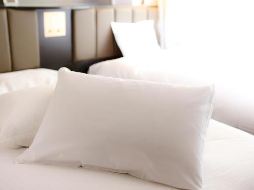 a pile of white pillows sitting on a bed at APA Hotel Osaka Kadomashi Ekimae in Kadoma