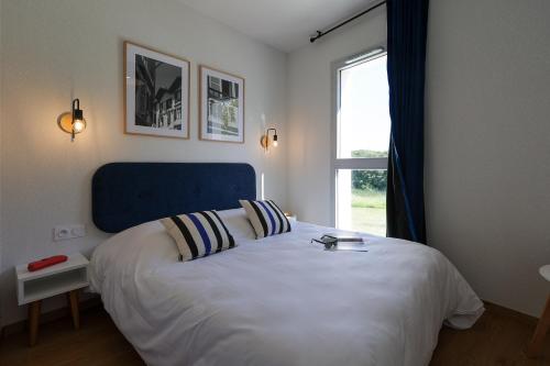 una camera da letto con un letto con testiera blu e una finestra di Résidence Néméa Le Domaine d'Uhaina a Urrugne