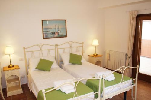 a bedroom with two beds with white sheets and green pillows at L'Alloggio-Not just rooms in Olbia