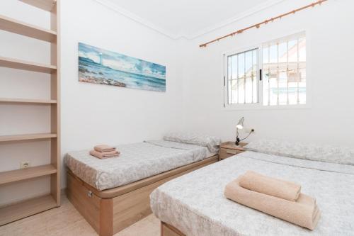 Cet hébergement comprend 2 lits dans une chambre dotée de murs blancs et de fenêtres. dans l'établissement 114 Sea Views Dream - Alicante Holiday, à Torrevieja