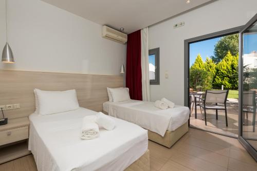 two beds in a room with a balcony at Princess Golden Beach Hotel in Chrysi Ammoudia
