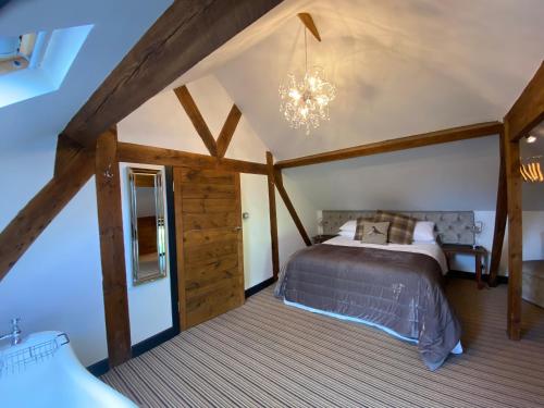 1 dormitorio con cama y lámpara de araña en Betsey Trotwood. Historic stylish 2-bed cottage. en Blundeston