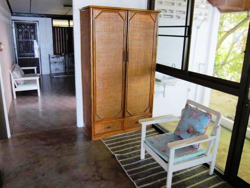a living room with a wooden cabinet and a chair at Bangpo Village in Ban Bang Po
