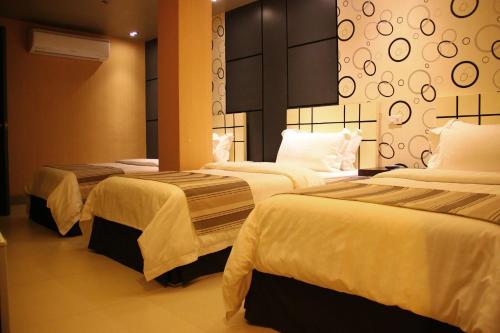 a hotel room with three beds with white sheets at Eloisa Royal Suites in Mactan