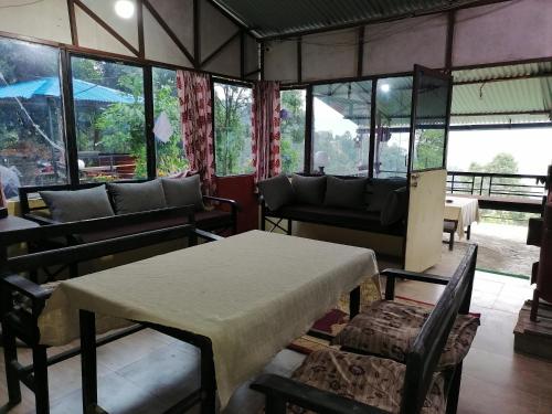 a room with a table and chairs and windows at Jungle Crown Organic Homestay in Nagarkot