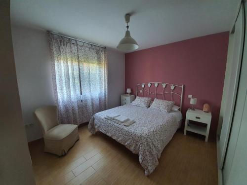 a bedroom with a large bed and a chair at El Rincon De Los Abuelos in Tudela de Duero